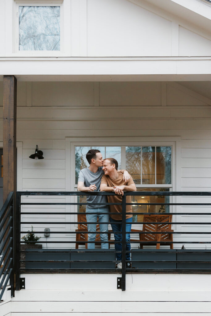 LGBTQ+ wedding photographer captured a couple kissing on their front porch during engagement photography session