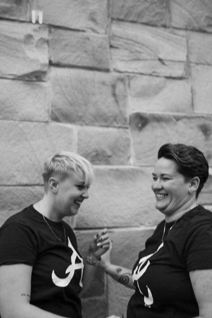 A queer couple holds hands laughing after their Atlanta engagement. This photo shows the joy and excitement after the engagement for this couple.