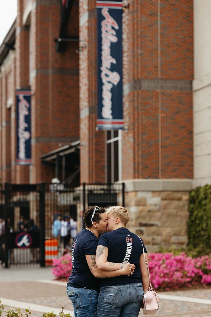 Mandee and Deliah holding hands after their Atlanta engagement. They're outside the Atlanta Braves stadium, kissing after getting engaged.