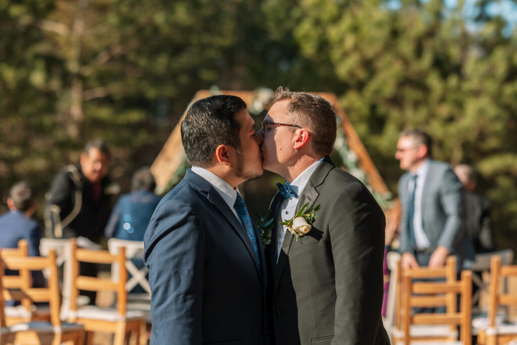 Two men kissing at an Atlanta wedding venue after getting married. The left man is in a navy blue suit and the right man is in a gray suit.